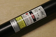 Photograph of a Helium-Neon laser tube. The label on the tube displays manufacturer information and specifications. 